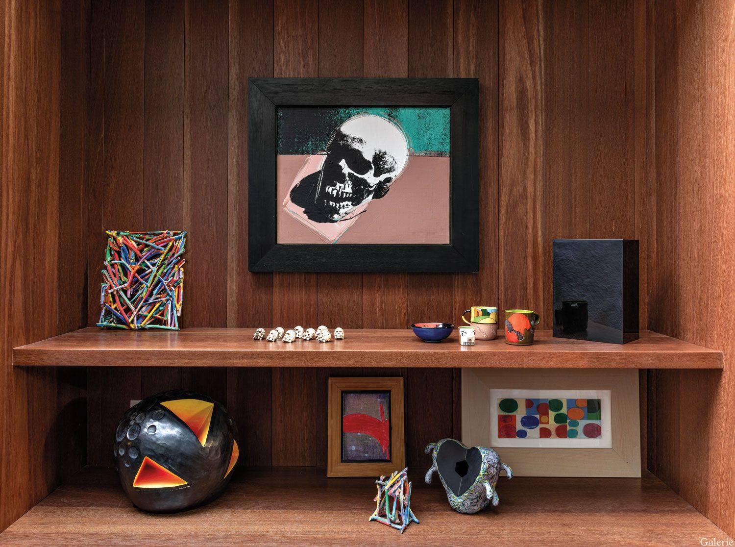 An Andy Warhol skull is grouped with works by Arnoldi, Ken Price, John McCracken, and Natalie Arnoldi in a bookcase.